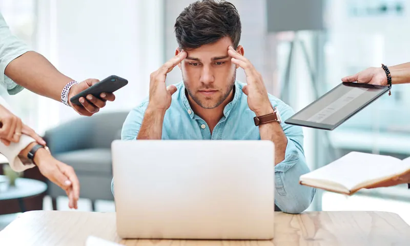 A stressed business owner juggling phones, a tablet and a laptop