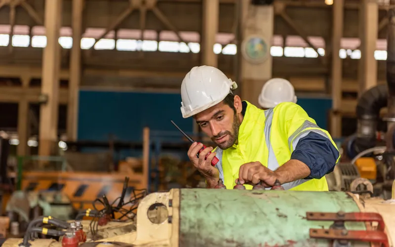 An engineer in a hard hat working on machinery