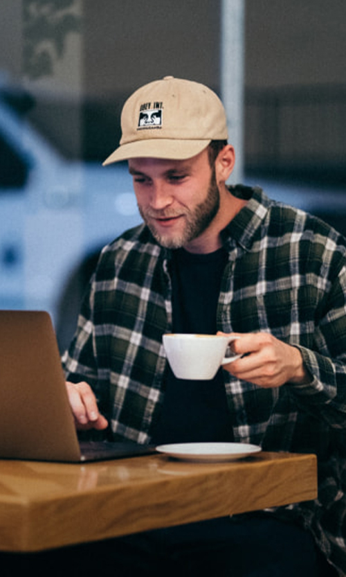 Man holding a mug and using laptop